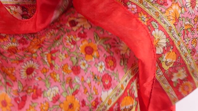 Vibrant silk fabric with orange and pink floral patterns falls onto a white background. This high-quality textile mockup is perfect for fashion industry promotions and cosmetic branding presentations.