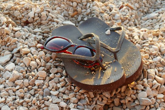 Flip flop sandals and sun glass on the beach with pebbles by the blue sea summer beach accessories