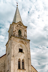 Obraz premium Historic stone church tower with spire against dramatic cloudy sky