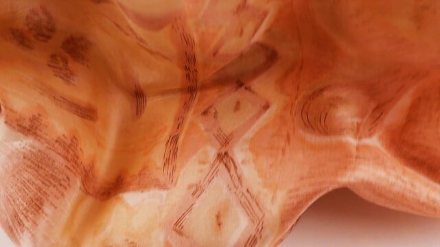 Peach silk scarf falls onto a white background. Light apricot satin fabric smoothly drops creating elegant folds. This luxury pastel textile is ideal for fashion industry and beauty brand commercials.