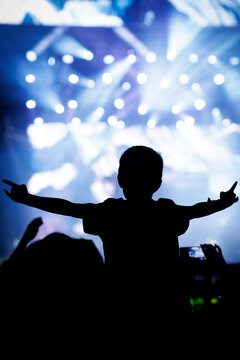 Child Silhouette Sitting on Shoulders at Bright Blue Light Concert