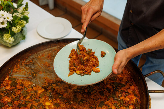 Chef Serving Traditional Spanish Paella onto Plate