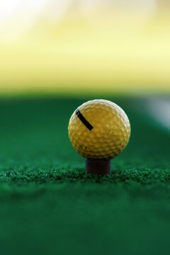 Yellow Golf Ball Placed on Tee over Green Artificial Turf