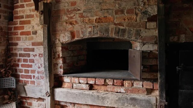 Close-up of a historic brick wood-fired oven with cast iron door set within a rustic heritage kitchen. Traditional masonry construction, aged brickwork, and old-world craftsmanship.
