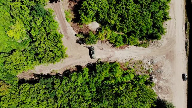 Aerial drone view of a mobile geotechnical drilling rig conducting soil investigation and ground sampling at a future construction site near a forested area in Sumy, Ukraine. The specialized drilling 