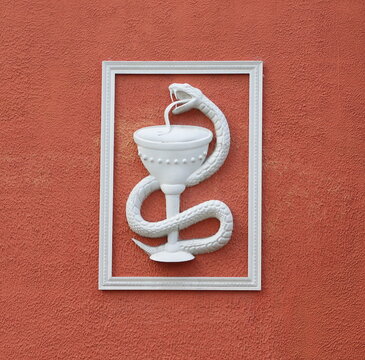 A white medical symbol in a frame on the red wall of a medical institution, Krestovsky Prospekt, Saint Petersburg, Russia, June 22, 2026