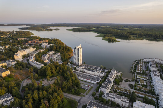 Aerial view of Kivenlahti featuring modern residential buildings, a tall apartment tower, lush forests, and the calm waters of the Gulf of Finland in Espoo, Uusimaa, Finland.