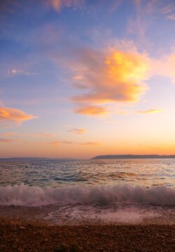 Waves on the wind with foam on the sea horizon with colorful clouds in sunset summer sunset background