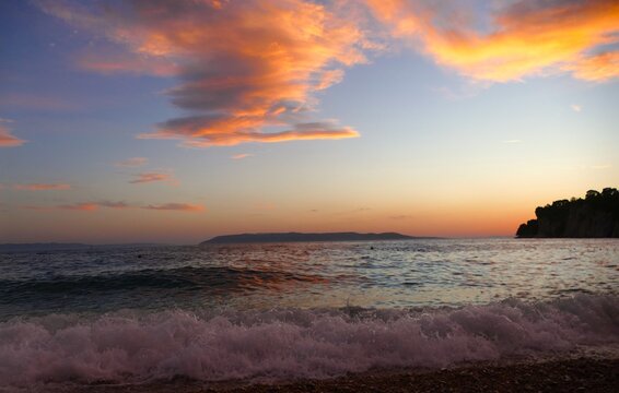 Waves on the wind with foam on the sea horizon with colorful clouds in sunset summer sunset background