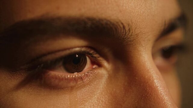 Showing teen face forming tear bead at lower eyelid, stretching and running down cheek in studio