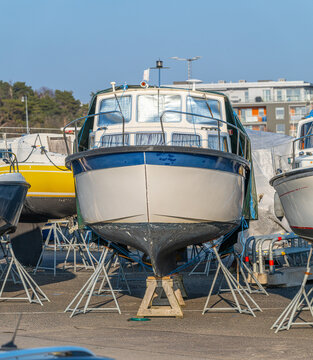 Front view of cabin boat elevated on stands in dry dock marina area.