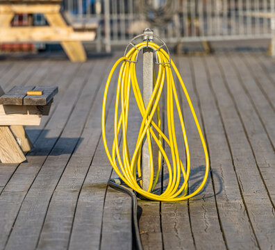 Yellow power cable coiled neatly on dock surface in marina utility area.
