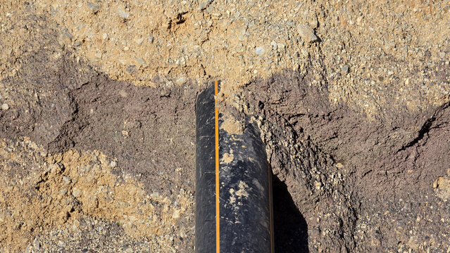 High density polyethylene gas pipe buried under layered soil in excavation trench