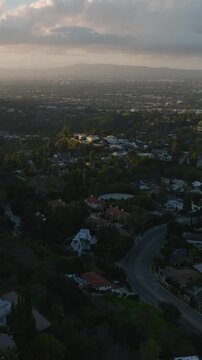 Aerial panoramic footage of houses in residential urban borough at sunset. Backwards fly above residencies in hills above city. Los Angeles, California, USA