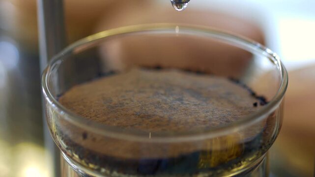 Close up drip coffee brewing process slow motion water drop falling into coffee grounds