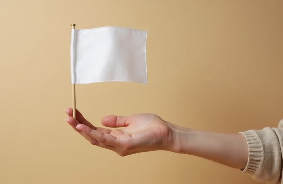 A hand offers a small blank white flag. This symbol can represent surrender or a new beginning. It suggests a pause or an offering of peace and hope.