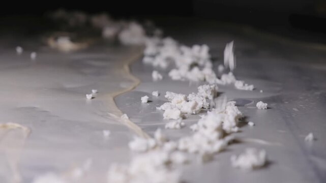 Close-up footage of cheese filling being sprinkled over thin yufka dough during b&ouml;rek preparation, showing handmade Turkish pastry technique, fresh ingredients and traditional kitchen work.