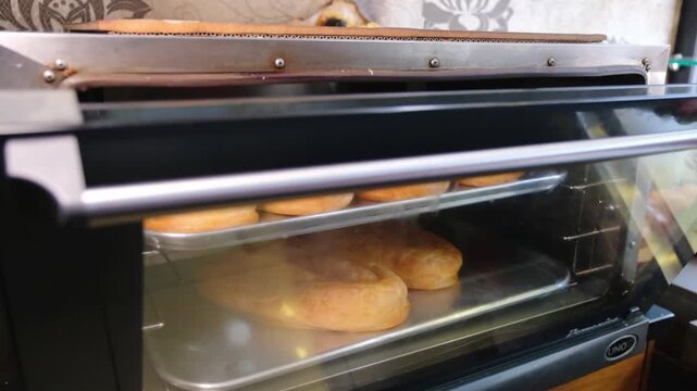 Close-up footage of freshly baked b&ouml;rek trays inside a hot oven, showing golden pastry layers, traditional Turkish food preparation, bakery service and restaurant-style baking process.