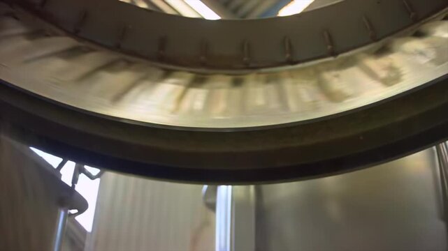 Industrial powder falling low angle inside processing vessel, rotating metal rim and bulk material flow for manufacturing, food production, chemical mixing, factory automation, process control media