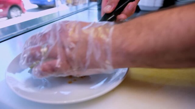 Close-up footage of freshly baked b&ouml;rek being placed onto a white plate with a spatula, showing crispy pastry layers, Turkish food service and restaurant-style plating preparation.