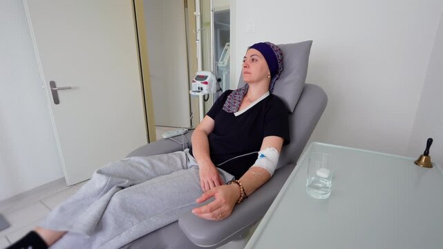 Female cancer patient receiving chemotherapy infusion in oncology clinic while resting in treatment chair, healthcare recovery setting expressing resilience, hope and healing