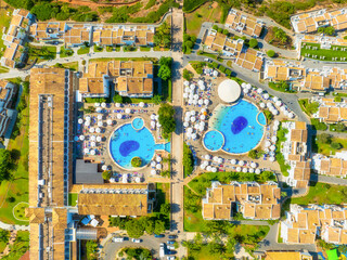 Obraz premium Aerial drone view of a modern residential neighborhood or resort area. Suburban streets with houses, hotel buildings, private swimming pools and people relaxing outdoors.