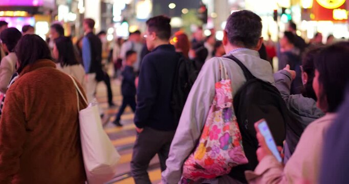Many people walk across large pedestrian crossing at Causeway Bay in slow motion, viewed from behind with blurred background to avoid recognizable faces, making it suitable for commercial use.