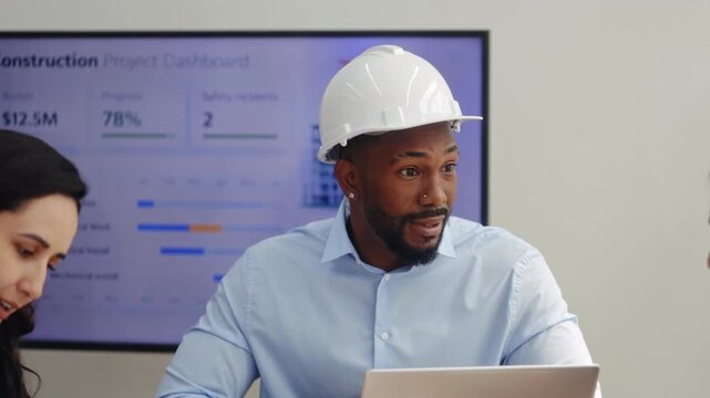 Portrait of African American engineer in helmet talks on construction project to colleagues in office. Multiethnic architect designers communicate in boardroom