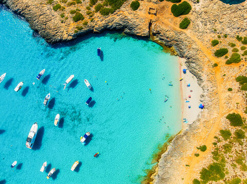 Aerial view of Cala Varques beach bay and turquoise sea in Mallorca, Spain. Scenic coastline landscape with boats and yachts in summer. Mediterranean nature and vacation destination from drone.