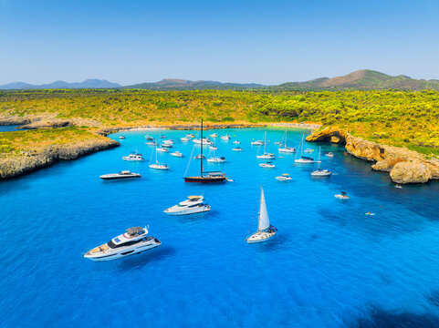 Aerial view of a bay and turquoise sea in Mallorca, Spain. Scenic coastline landscape with boats and yachts in summer. Mediterranean nature and vacation destination from drone. Wallpaper, background.
