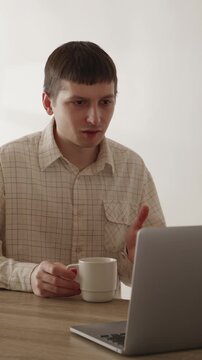 Young man waving hand during video conference call on laptop at home