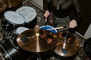 Fototapeta premium Young adult woman playing drum kit during band rehearsal, performing rhythm and music production. Useful for entertainment marketing, music school promotion, overhead shot