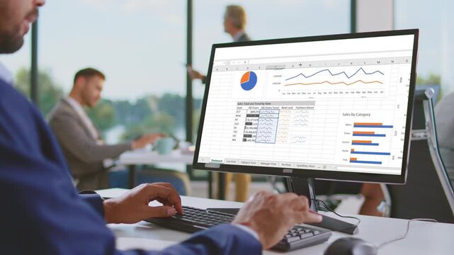 Man analyzing financial charts on computer screen in modern office environment, dynamic footage.