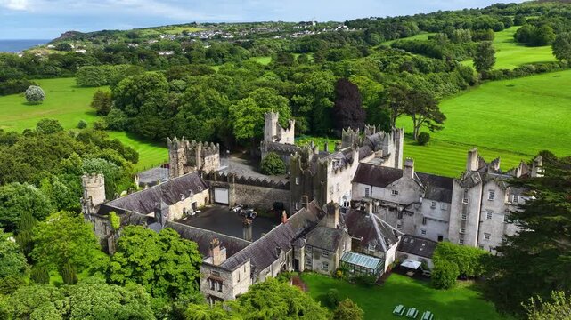 Howth castle estate on Howth peninsula near Dublin, aerial view, orbiting drone shot of Howth castle in Ireland, medieval Irish castle ruins, travel in Ireland