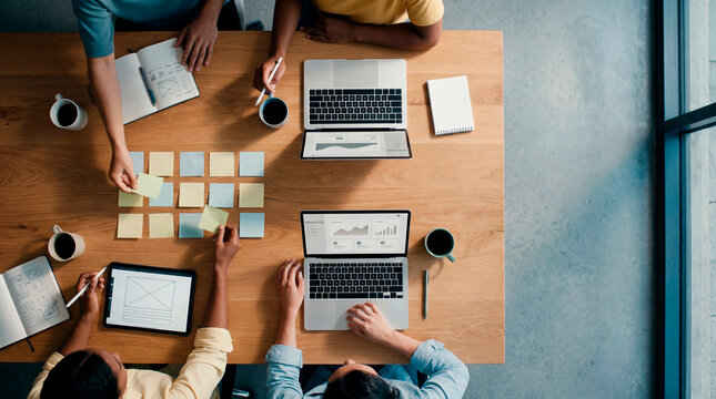 Overhead view of team planning digital strategy with laptops and analytics on desk