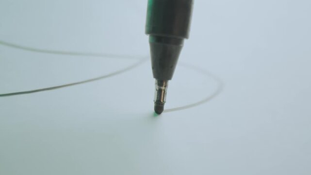 Close-up macro shot of black marker pen drawing lines and scribbles on white paper, artistic process footage.