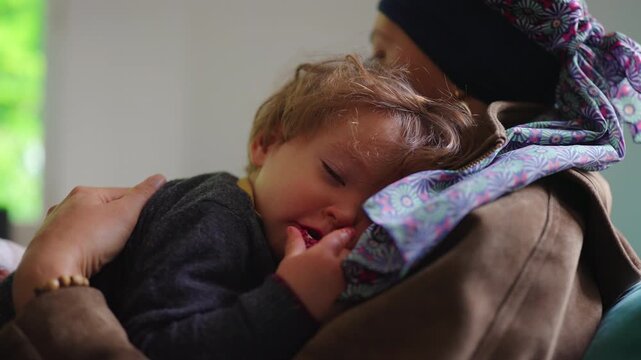 Toddler resting in mother arms at home, close family connection highlighting attachment, comfort, trust and emotional security