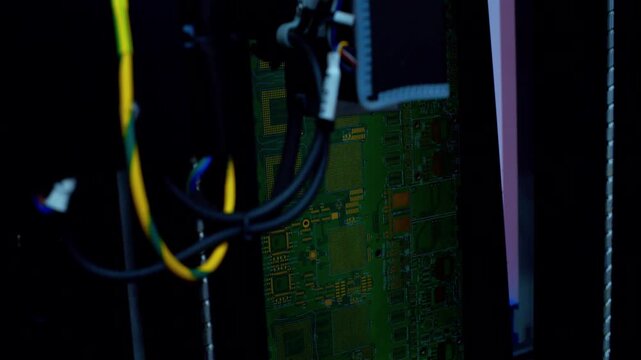 Industrial robot checks the assembly of elements on a circuit board. High-tech manufacturing process, automated microelectronics inspection, and precision hardware quality control in a smart factory.