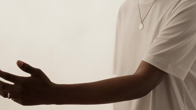 Slowmo shot of African American young man and Caucasian young woman reaching out and gently touching hands in white studio. Suitable for diversity, inclusion, and relationship marketing campaigns