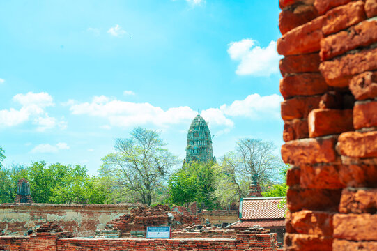 Ancient headless Buddha statues lining the red brick wall at Wat Mahathat in Ayutthaya, Thailand.
