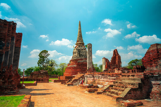 Ancient headless Buddha statues lining the red brick wall at Wat Mahathat in Ayutthaya, Thailand.