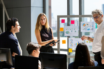 Obraz premium Senior supervisor is giving adivce to young staff about market trend while working in corporation with modern luxury office for business and education concept