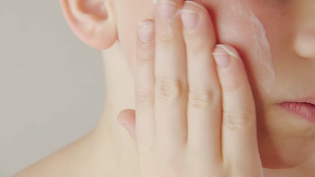 teenage boy applying acne cream, Teen boy focused on facial skincare, highlighting self-image issues and teenage skin concerns