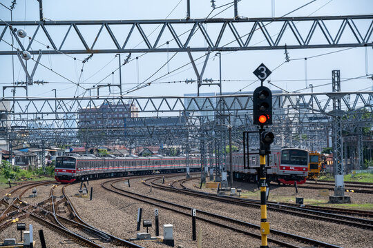 Jakarta, Indonesia - May 28, 2026: Two KAI Commuter electric trains pass each other on curved tracks at the multi-track railway junction near Jatinegara Station.
