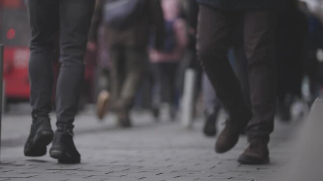 Pedestrians walking on city street outdoors on a cloudy day slow motion view from behind.