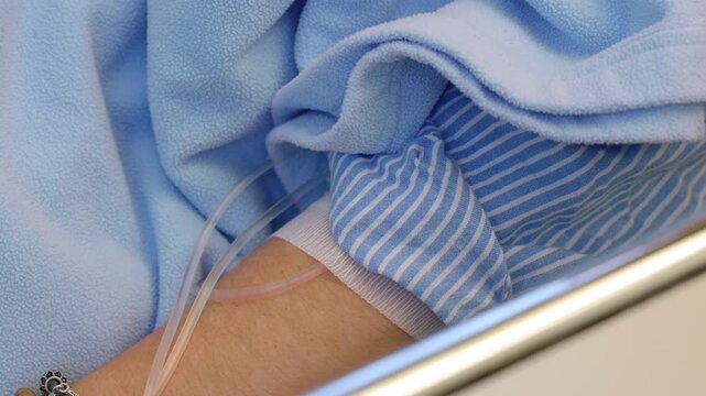 Intravenous line connected to patient arm during medical treatment in healthcare facility, highlighting clinical care, therapy administration, recovery and wellness support