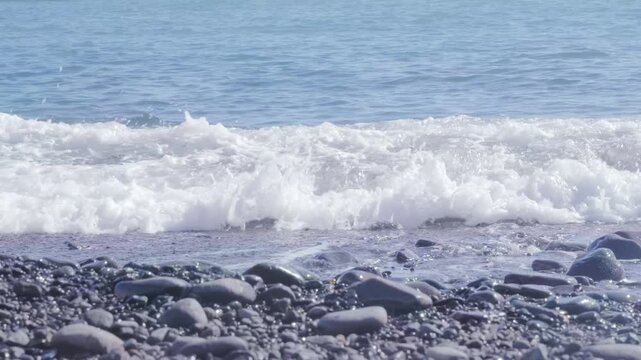 Black Volcanic sand beach and blue water ocean in Madeira, coast Portugal, Atlantic waves sparkle in sun, warm Gulf Stream water flows, peaceful energy, marine life