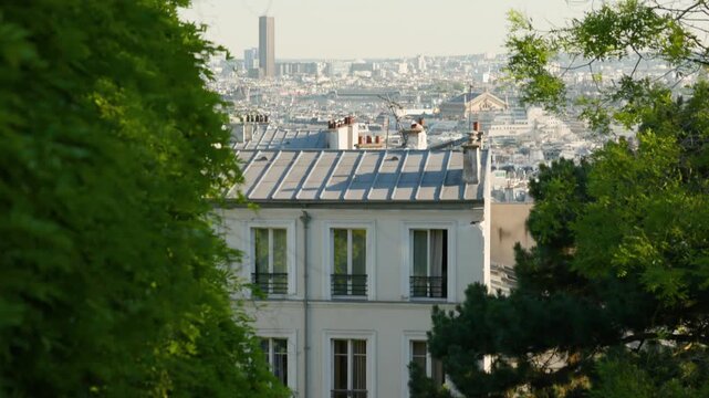 A camera panning up over classic zinc rooftops of Montmartre to reveal a wide Paris cityscape with the iconic Tour Montparnasse skyscraper in the far distance.