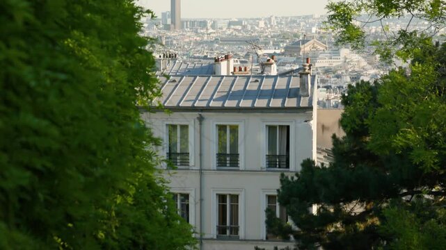 A camera panning up over classic zinc rooftops of Montmartre to reveal a wide Paris cityscape with the iconic Tour Montparnasse skyscraper in the far distance.