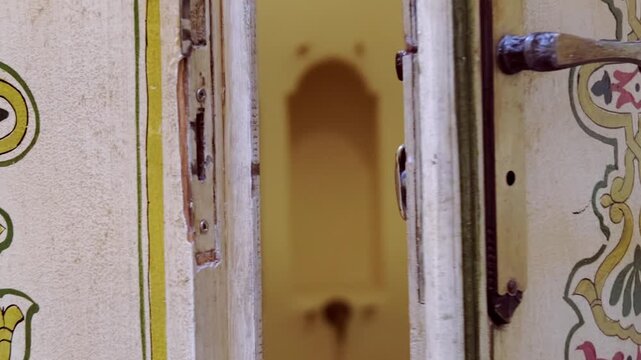 Closing vintage Moroccan door with carved wood, female hands in motion, mystery, elegance, riad interior, private space